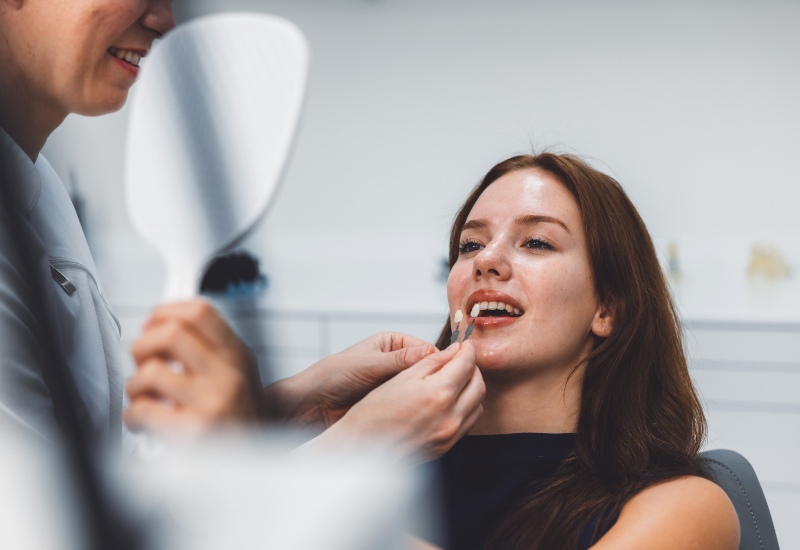 A dentist uses a shade guide for cosmetic dental treatments during consultation in St. Louis, MO