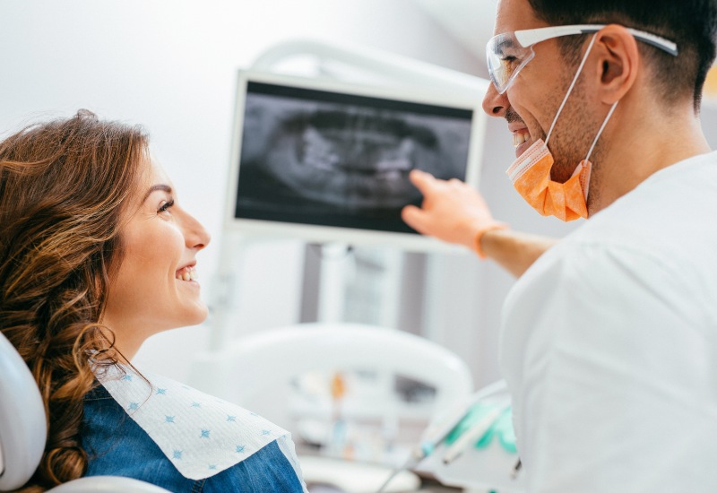 A dentist shows the X-ray & explains the restorative procedure to a patient in St. Louis, MO